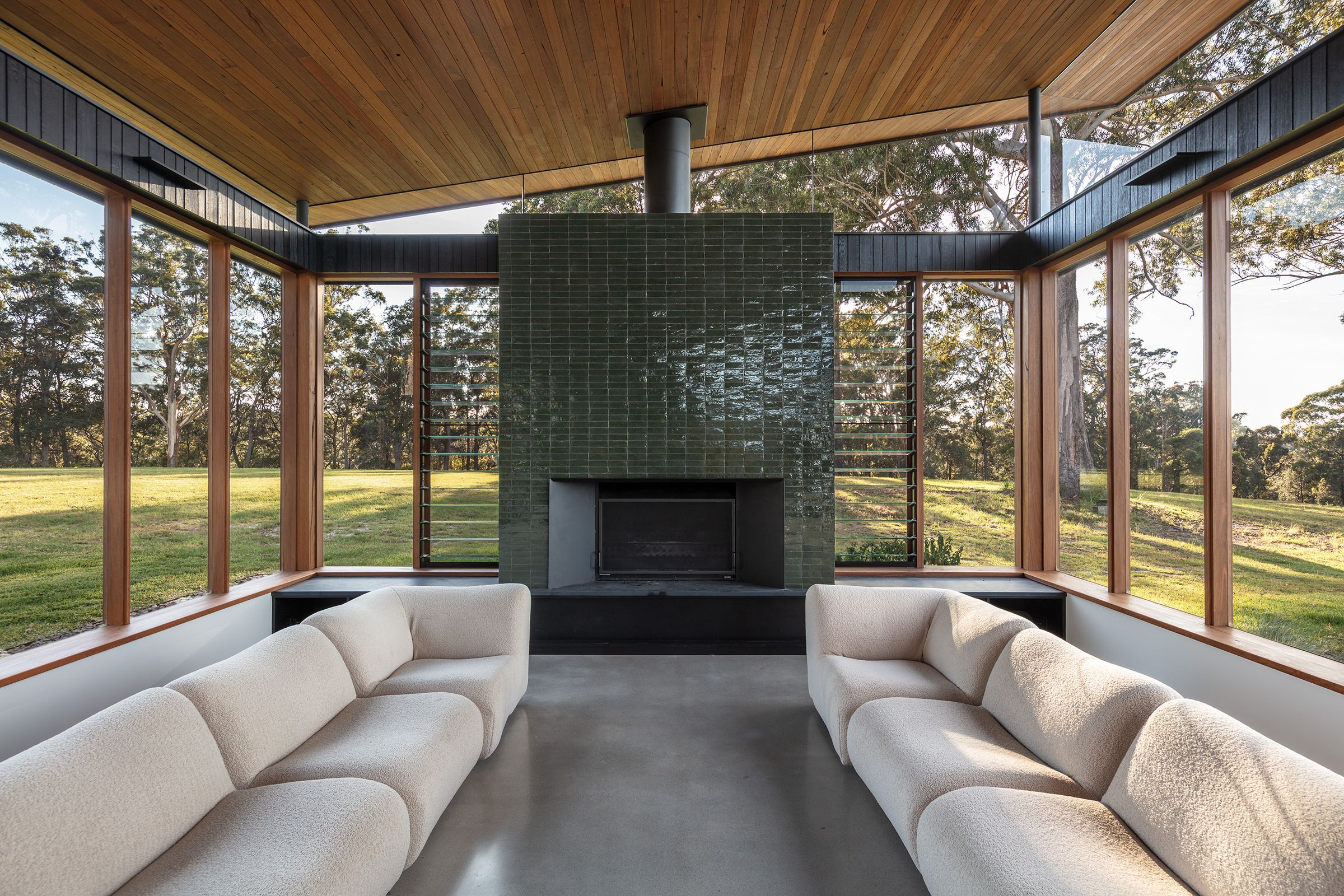 Lounge around a green tiled fireplace with glass walls on three sides