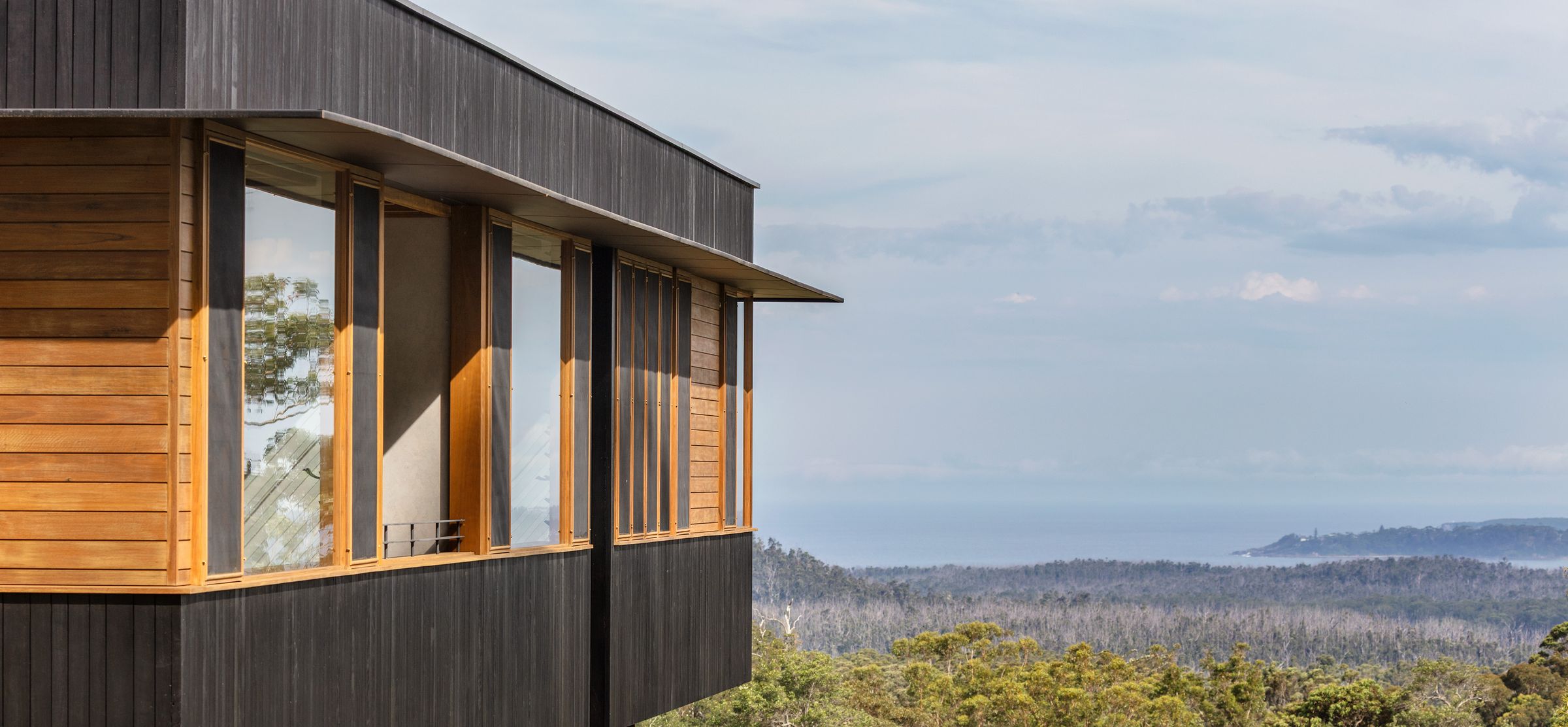 Timber clad bedroom wing looking over bushland to the ocean